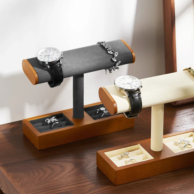 Deux présentoirs à bijoux en bois avec supports en T présentent des montres, des bracelets et des bagues sur une surface en bois à la lumière naturelle.