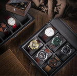 Une collection de montres de luxe Boites Lefiguet exposées dans une boîte à montres Boite 10 Montres Compartiments Larges, posée sur une table en bois avec un arrière-plan flou représentant une personne examinant une autre montre.