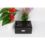 Une boîte à bijoux en bois Boites Lefiguet noire avec une fleur violette à l'intérieur.