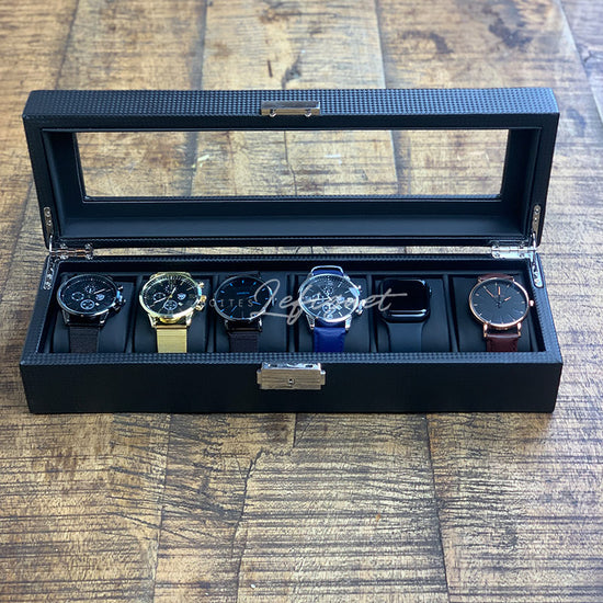 Quatre montres Boite Black Carbon Élégance 6 slots dans une boîte noire sur une table en bois. (Nom de marque : Boites-lefiguet.com)